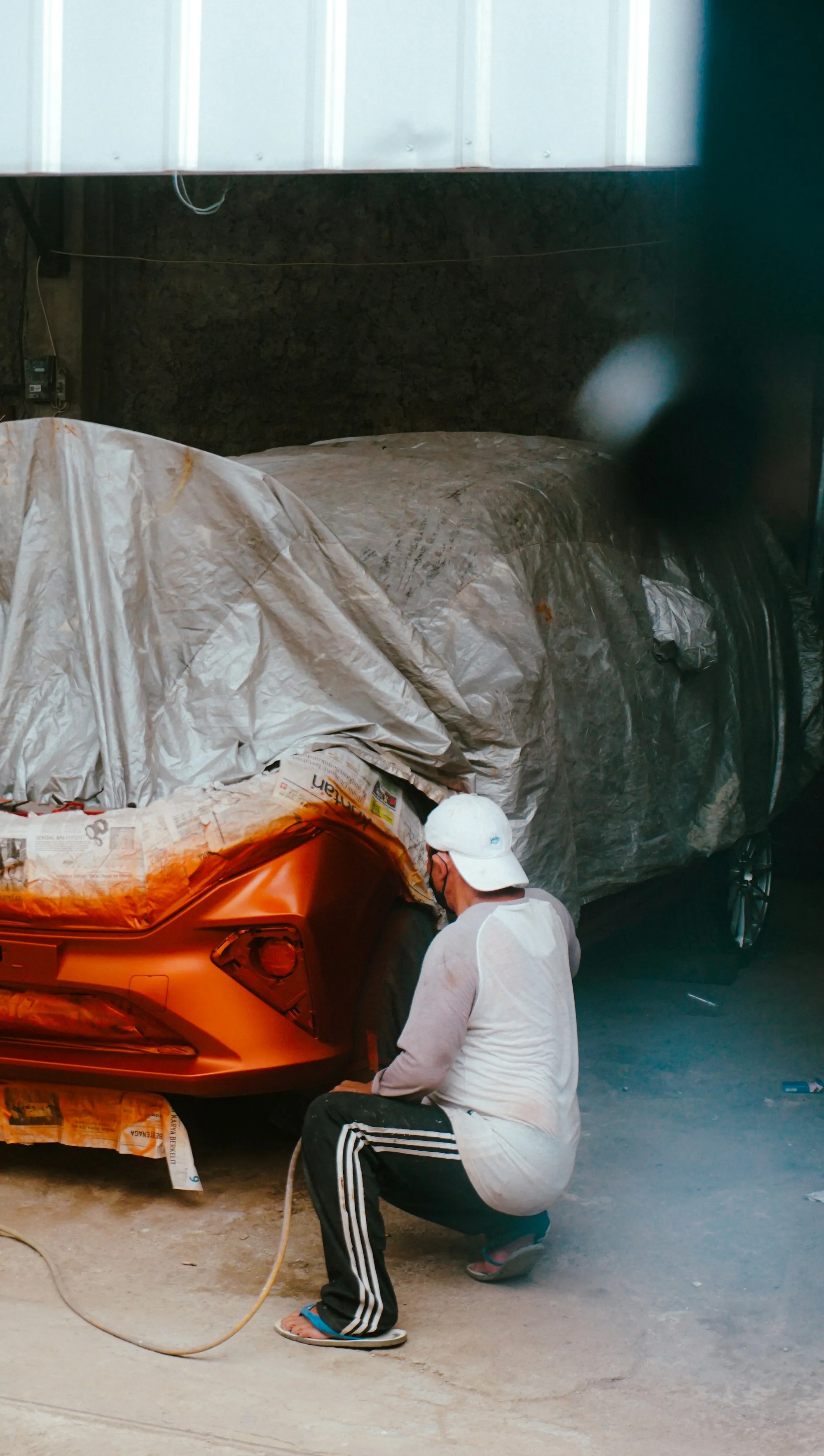 Technician masking a car before it goes into the paint booth